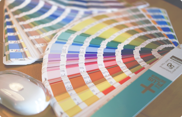 Pantone colour books fanned out on a wood background.